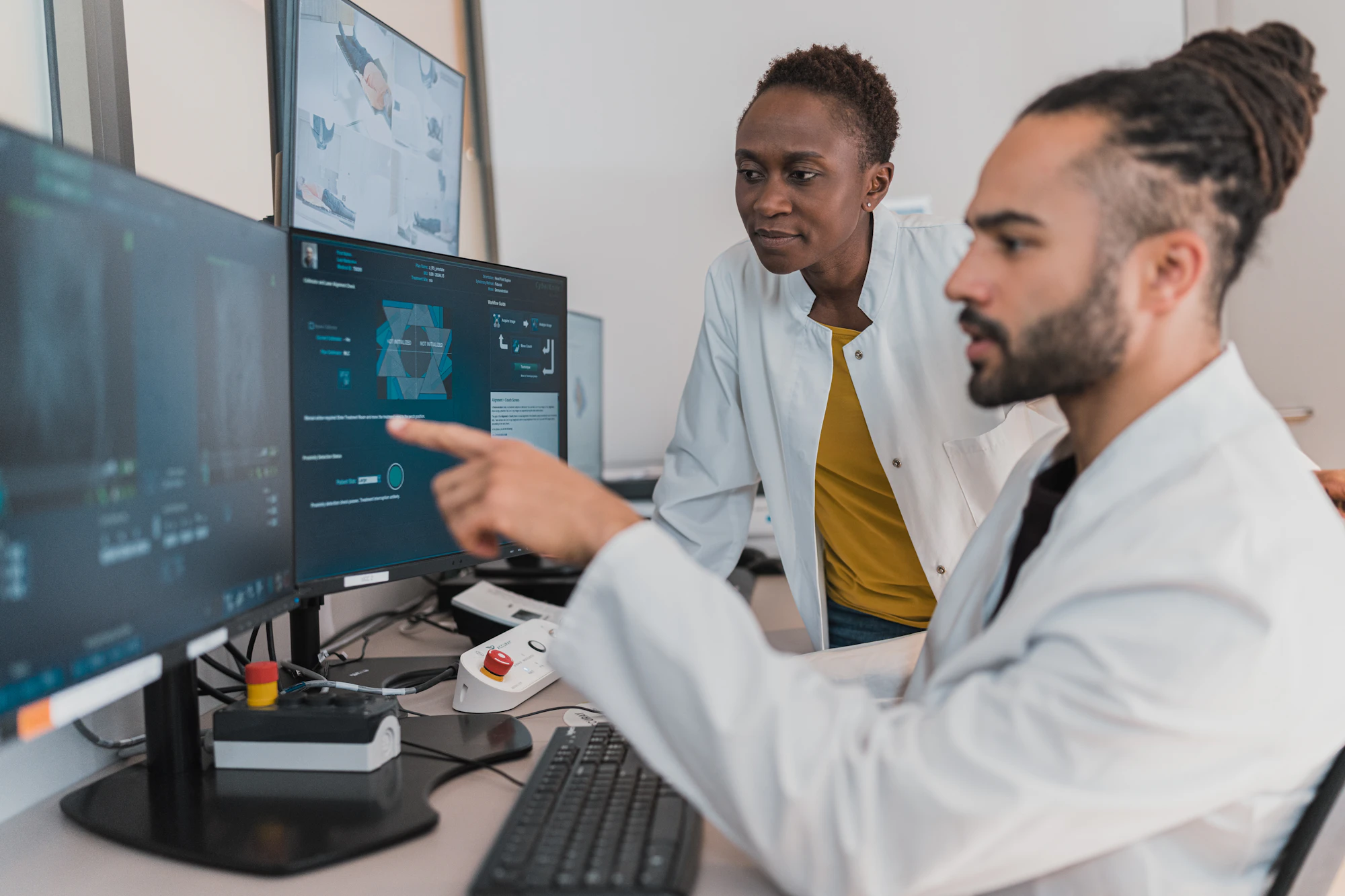 Two clinicians in white coats review images together at a workstation